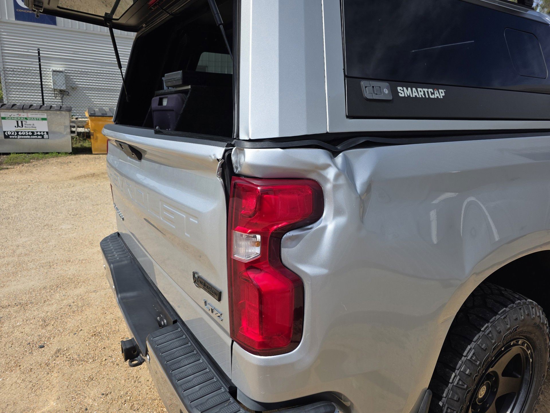 Dent in the rear quarter panel of a silver Chevrolet Silverado